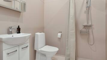 Een moderne badkamer met een wit wastafel, toilet en douche.