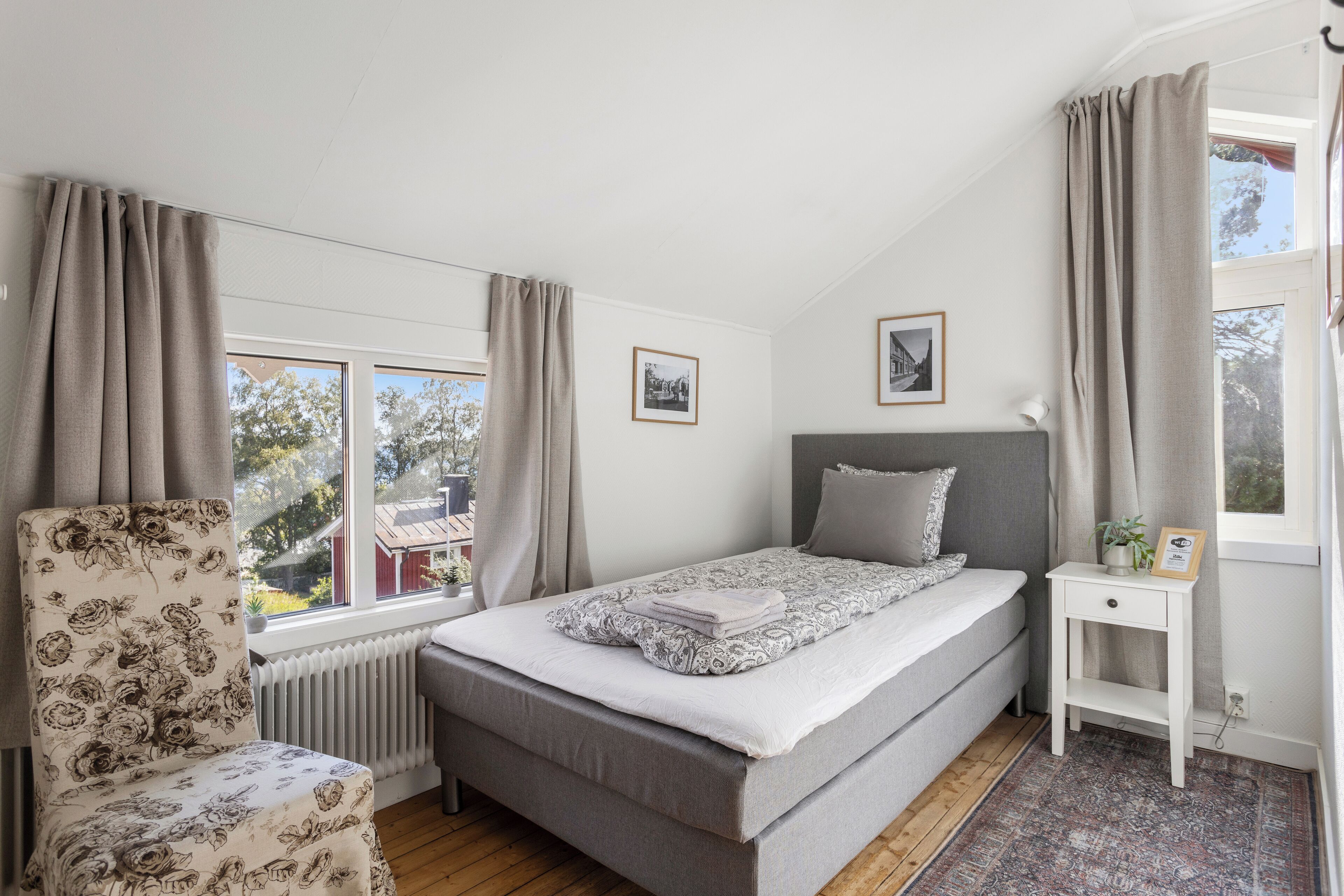 Une chambre à coucher avec un lit, une chaise, une table de chevet et une fenêtre.