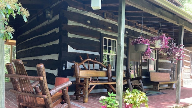 A rustic wooden cabin with a porch, rocking chairs, and hanging flower baskets. - Tarry Moore Cottage ... on Foxburg's historic fairways (Foxburg)