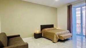 A bedroom with a bed, a nightstand, a sofa, and a balcony. - Nerisa home  (Naples)