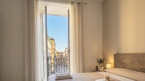 A hotel room with a large bed, a view of the city through a window, and a balcony. - Nerisa home  (Naples)