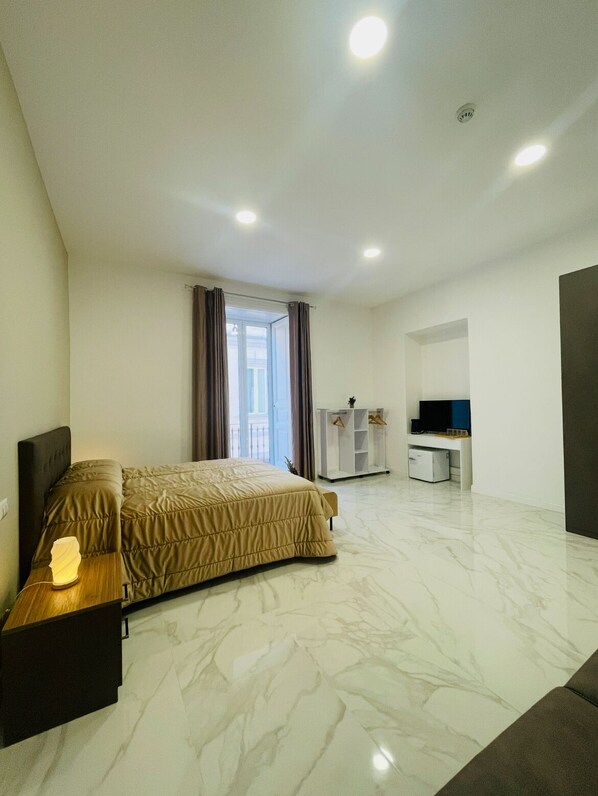 A modern hotel room with a bed, a desk, a TV, and a wardrobe. - Nerisa home (Naples)
