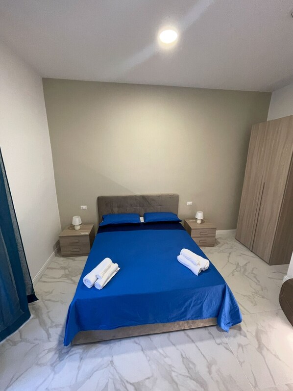 A bedroom with a bed, two bedside tables, a wardrobe, and a ceiling light. - Nerisa home (Naples)