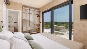A modern bedroom with a large bed, a walk-in closet, and a balcony with a view.