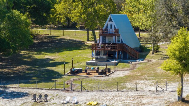 Un chalet au bord du lac, doté d’une terrasse, de meubles de jardin et d’un quai avec des kayaks.