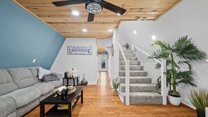 Un salon moderne avec un canapé gris, une table basse noire et un escalier menant à l’étage supérieur.