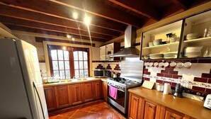A kitchen with wooden cabinets, a stove, and a tiled backsplash. - Gingerbread House – sunset, relaxing & warm (Katoomba)