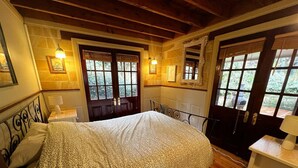 A bedroom with a large bed, wooden flooring, a dresser, and a window with a view of greenery. - Gingerbread House – sunset, relaxing & warm (Katoomba)