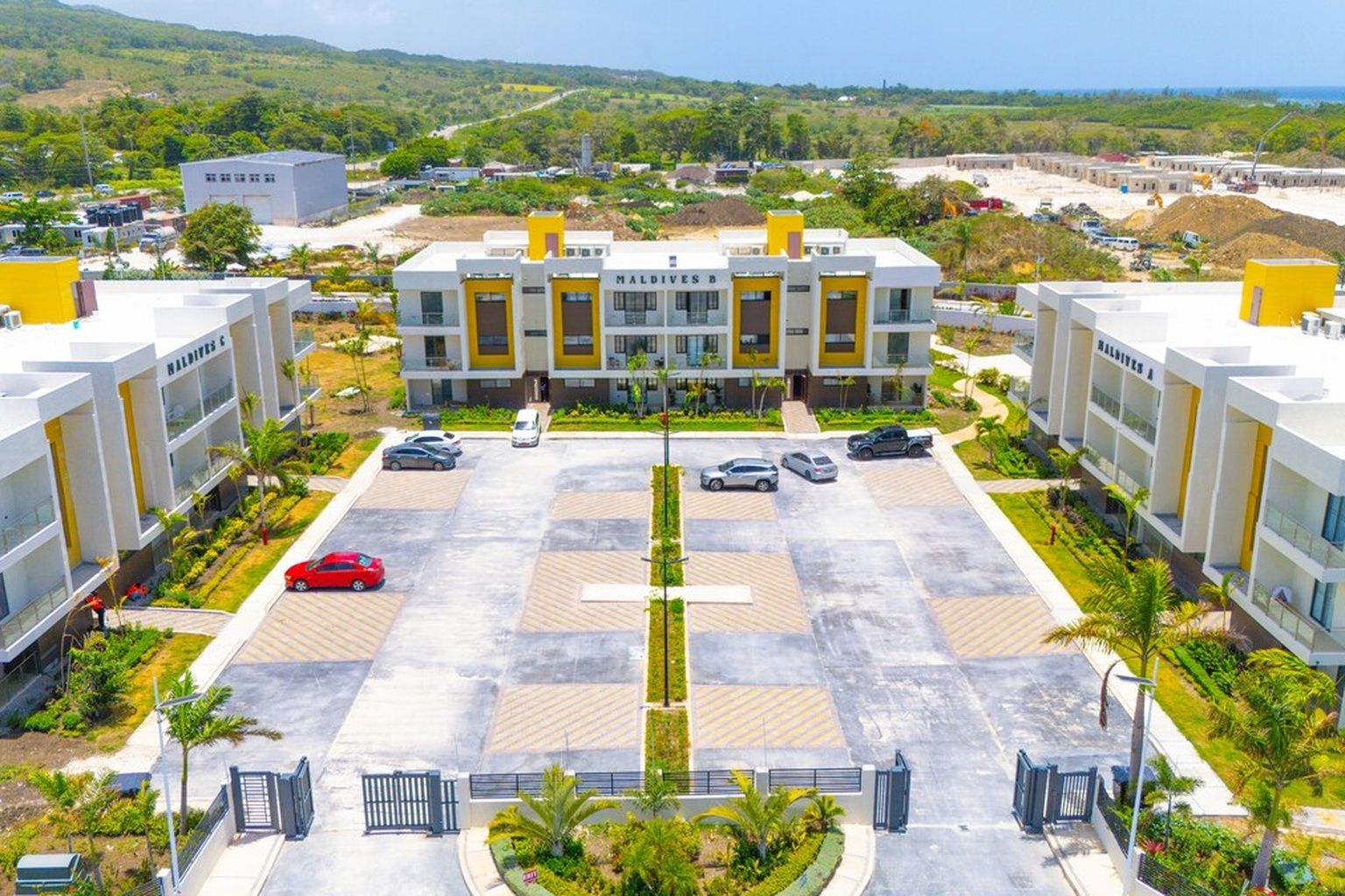 A modern hotel with a central building, multiple parking spaces, and a surrounding landscaped area.