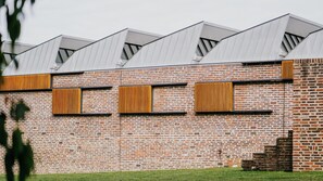 Un bâtiment en briques au design moderne, doté de grandes fenêtres avec des persiennes en bois et d’un toit plat.
