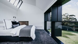 A modern bedroom with a large bed, a view of the outdoors, and a skylight. - Alkina Lodge Namu Great Ocean Road (Wattle Hill)