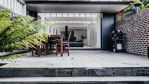 An outdoor patio with a dining table and chairs, a brick wall, and a gas stove. - Alkina Lodge Namu Great Ocean Road (Wattle Hill)