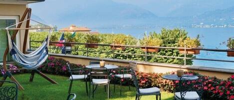 A terrace with a hammock, outdoor seating, and a view of a lake and mountains.