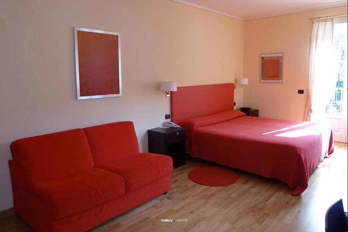 A room with two beds, a sofa, a nightstand, and a small table.