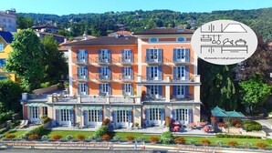 Un hotel de varios pisos con balcones, mobiliario exterior y un jardín.