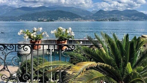 Un balcón con plantas en macetas y vistas al mar y a las montañas.