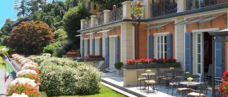 A multi-story hotel with outdoor seating and well-maintained gardens.