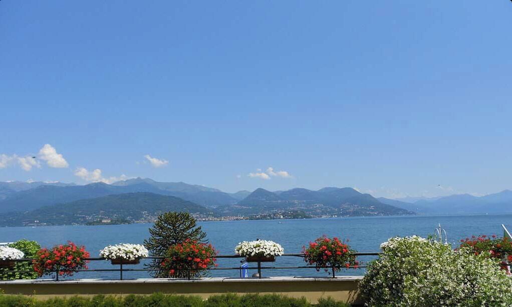 A terrace with outdoor seating, a view of a lake, and mountains in the background.