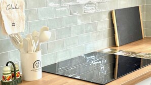A kitchen with a black stovetop, white cabinets, and a tiled backsplash. - Chez Grand-Mère unique experience, close to the center, free parking (Metz)