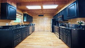 A kitchen with wooden floors, black cabinets, and a central island.