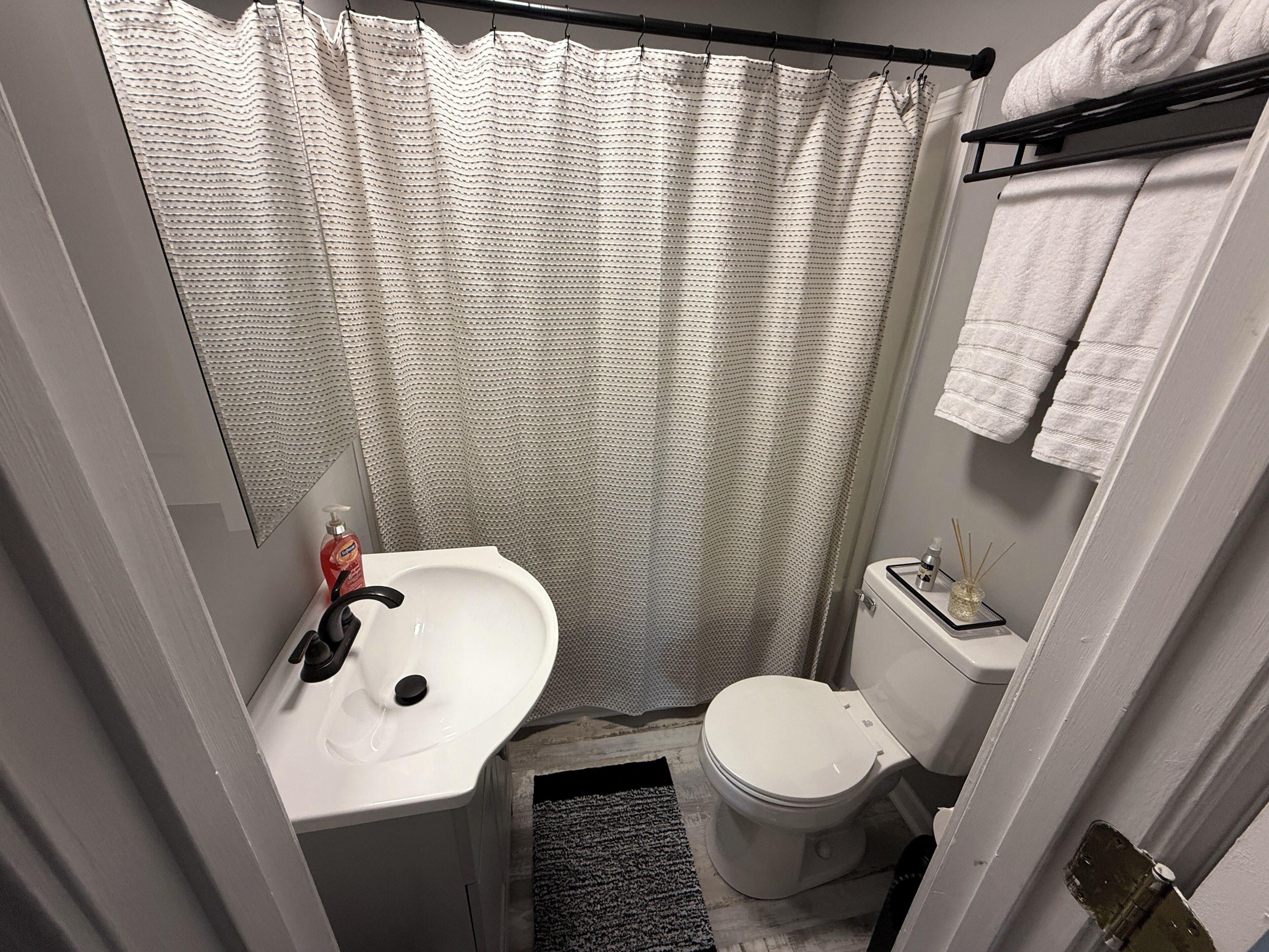 A small bathroom with a white sink, toilet, and shower curtain.