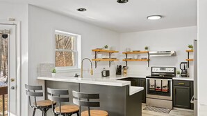 Een moderne keuken met een centraal eiland, barkrukken en inbouwplanken.