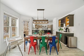 Une cuisine moderne avec une table à manger, des chaises colorées et un meuble encastré.