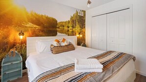 Een slaapkamer met een bed, nachtkastje, behang en een kledingkast.