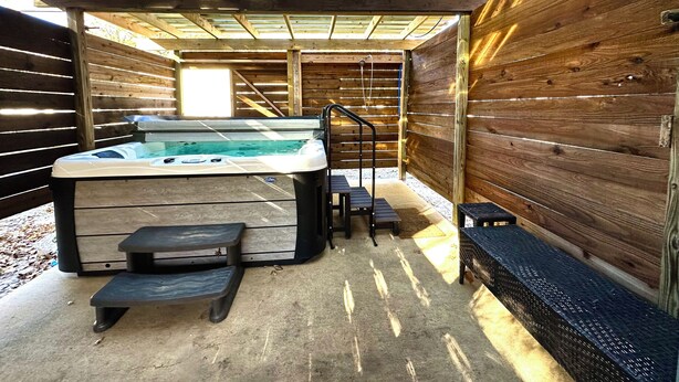 A hot tub under a wooden pergola with steps leading up to it.