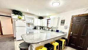 A modern kitchen with white cabinets, a granite countertop, and a coffee-themed wall decoration.