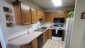 A kitchen with wooden cabinets, a microwave, a stove, and a refrigerator. - In the heart of Durango (Durango)