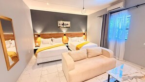 Une chambre d’hôtel avec deux lits, un canapé, un sol en marbre, un tableau au mur et une fenêtre avec des rideaux.