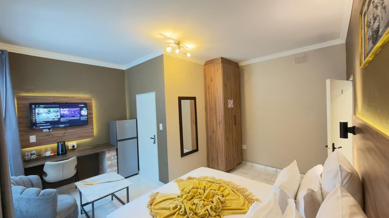 A hotel room with a bed, a desk, a TV, and a wardrobe.