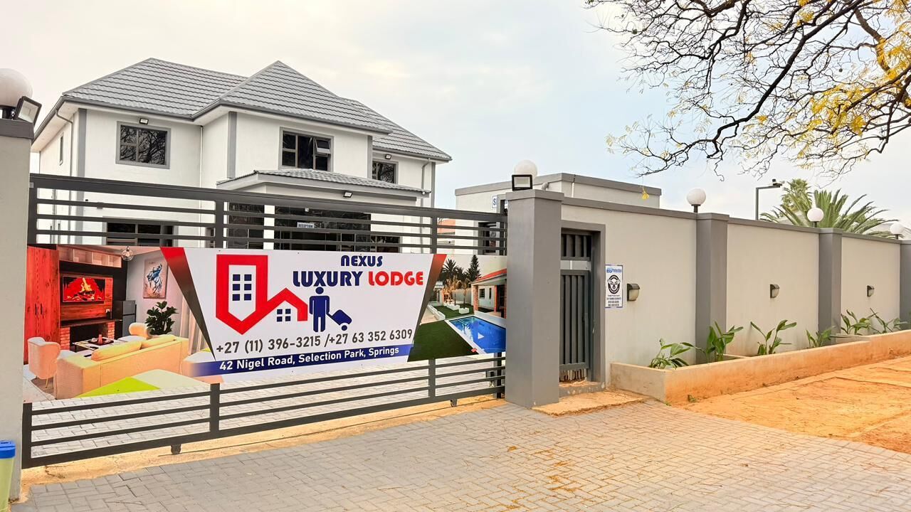 A luxury lodge with a gated entrance, a signboard, and a landscaped area with plants.