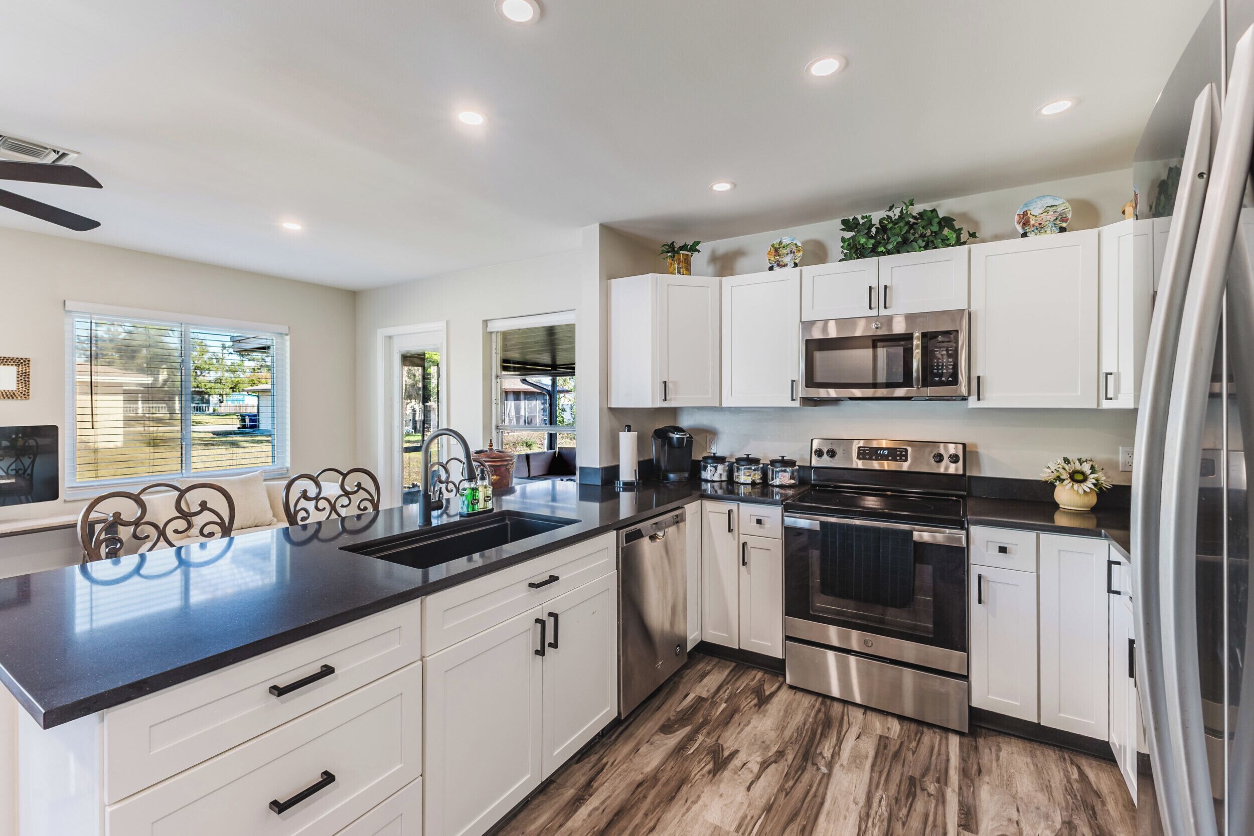 A modern kitchen with white cabinets, stainless steel appliances, and a black countertop.