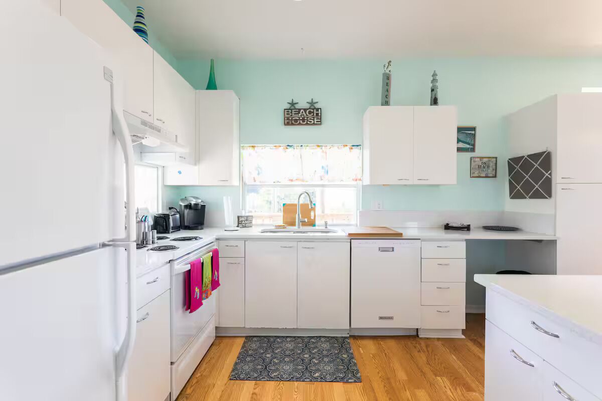 A modern kitchen with white cabinets, a black countertop, and a window with a view.
