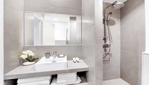 Een moderne badkamer met een wit wastafelmeubel, een grote spiegel en een douche met een handdouche.