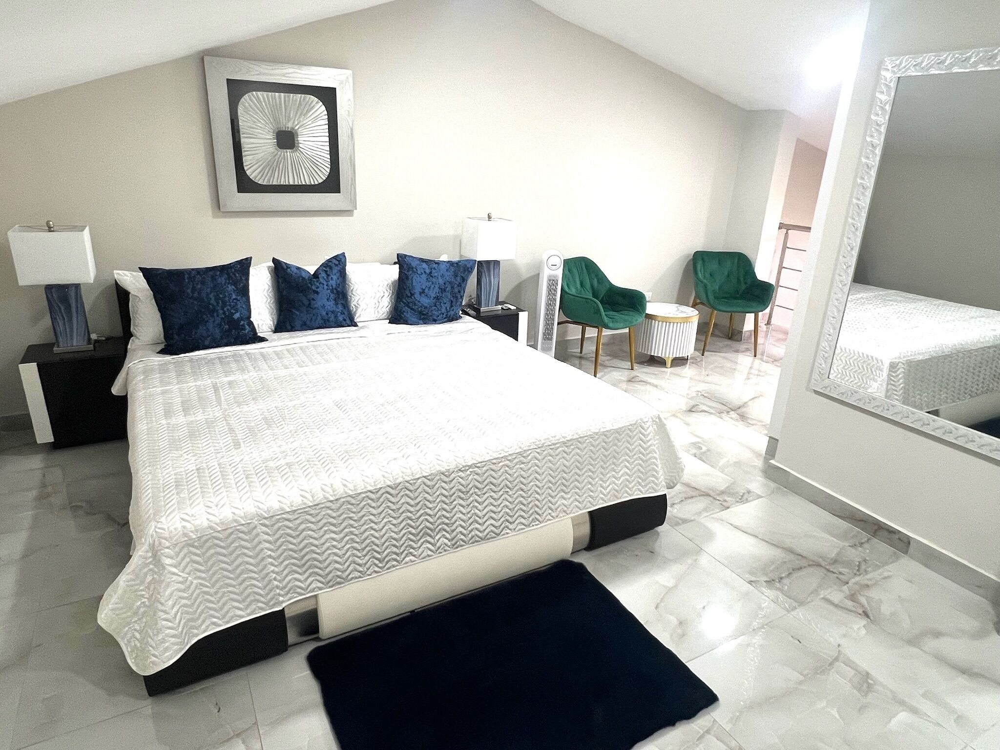 Une chambre moderne avec un grand lit, une table de chevet, une chaise et un miroir.
