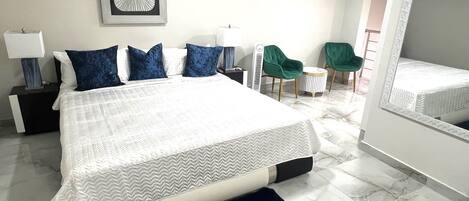 Une chambre moderne avec un grand lit, une table de chevet, une chaise et un miroir.
