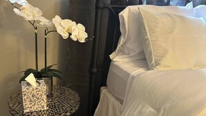 A neatly made bed with white bedding, a small round table with a patterned box, and a white orchid plant on the nightstand. - Charming Newly remodeled 3Br2Ba (San Angelo)