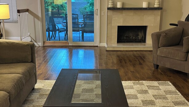A living room with a dark wooden coffee table, a beige sofa, a brown sofa, and a fireplace.