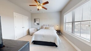 A bedroom with a bed, a ceiling fan, a chair, a nightstand, and a window with blinds. - Northgate Landing-  Walk to A&M & Nightlife (Bryan)