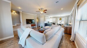A spacious living room with a large sectional sofa, a coffee table, and a ceiling fan. - Northgate Landing-  Walk to A&M & Nightlife (Bryan)