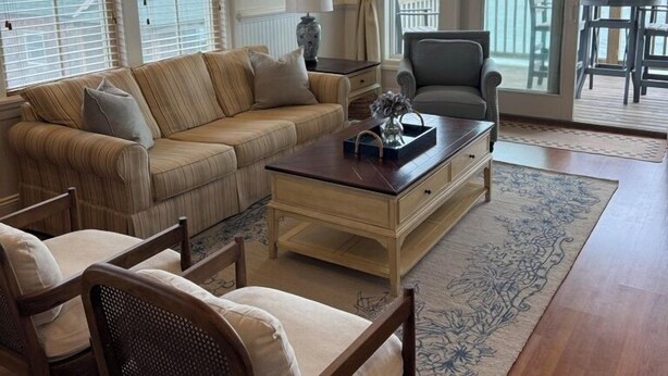 A living room with a sofa, armchairs, a coffee table, and a view of the ocean through large windows. - NEW listing! Sail Away - Ocean front TOP floor condo in charming Rodanthe (Rodanthe)