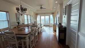 A spacious dining area with a wooden table and chairs, a chandelier, and a view to the outside. - NEW listing! Sail Away - Ocean front TOP floor condo in charming Rodanthe (Rodanthe)