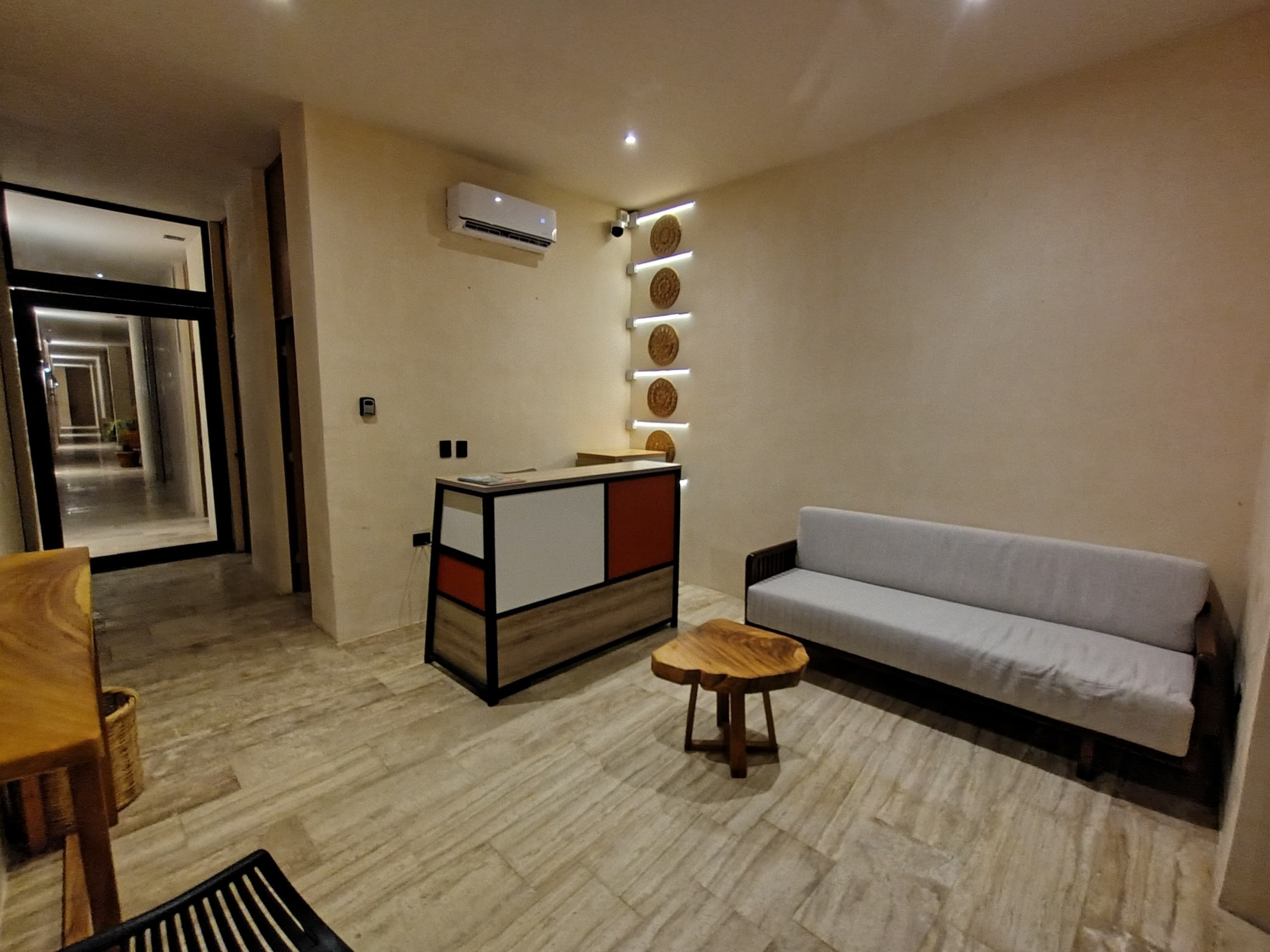 Een moderne woonkamer met een bank, een klein houten tafeltje, een decoratieve wandunit en een airconditioning.