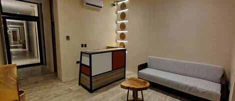 Een moderne woonkamer met een bank, een klein houten tafeltje, een decoratieve wandunit en een airconditioning.