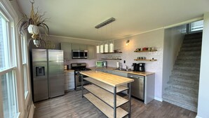 A modern kitchen with stainless steel appliances, a wooden island, and a built-in microwave.
