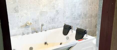 A modern bathroom with a freestanding bathtub, a large mirror, and a tiled backsplash.