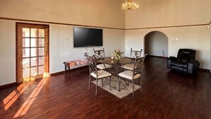 Un comedor con una mesa redonda, sillas, una araña, un televisor y una chimenea.